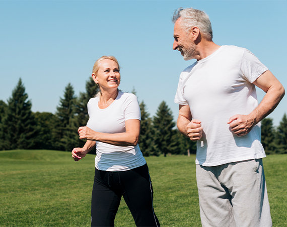 Fit couple running in park after achieving weight loss goals through medical weight loss program.